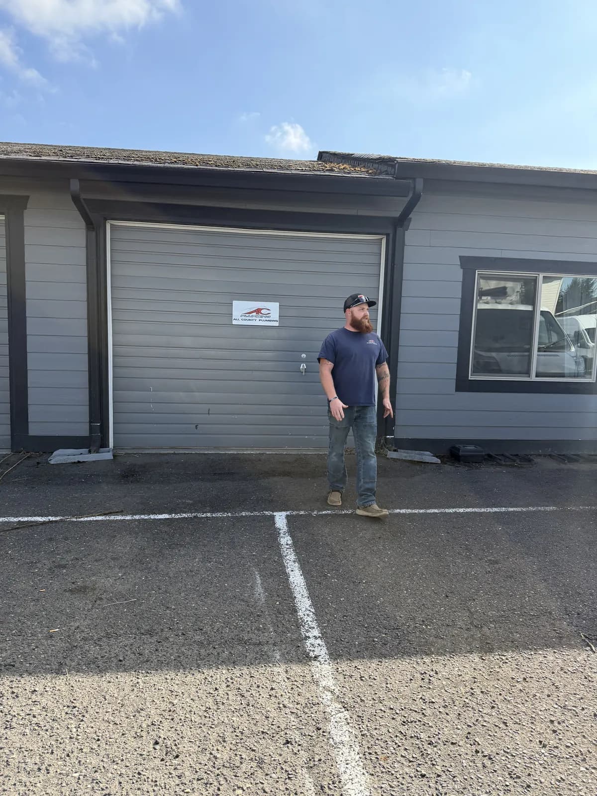 Crew member in a navy All County shirt in front of the shop roll-up door