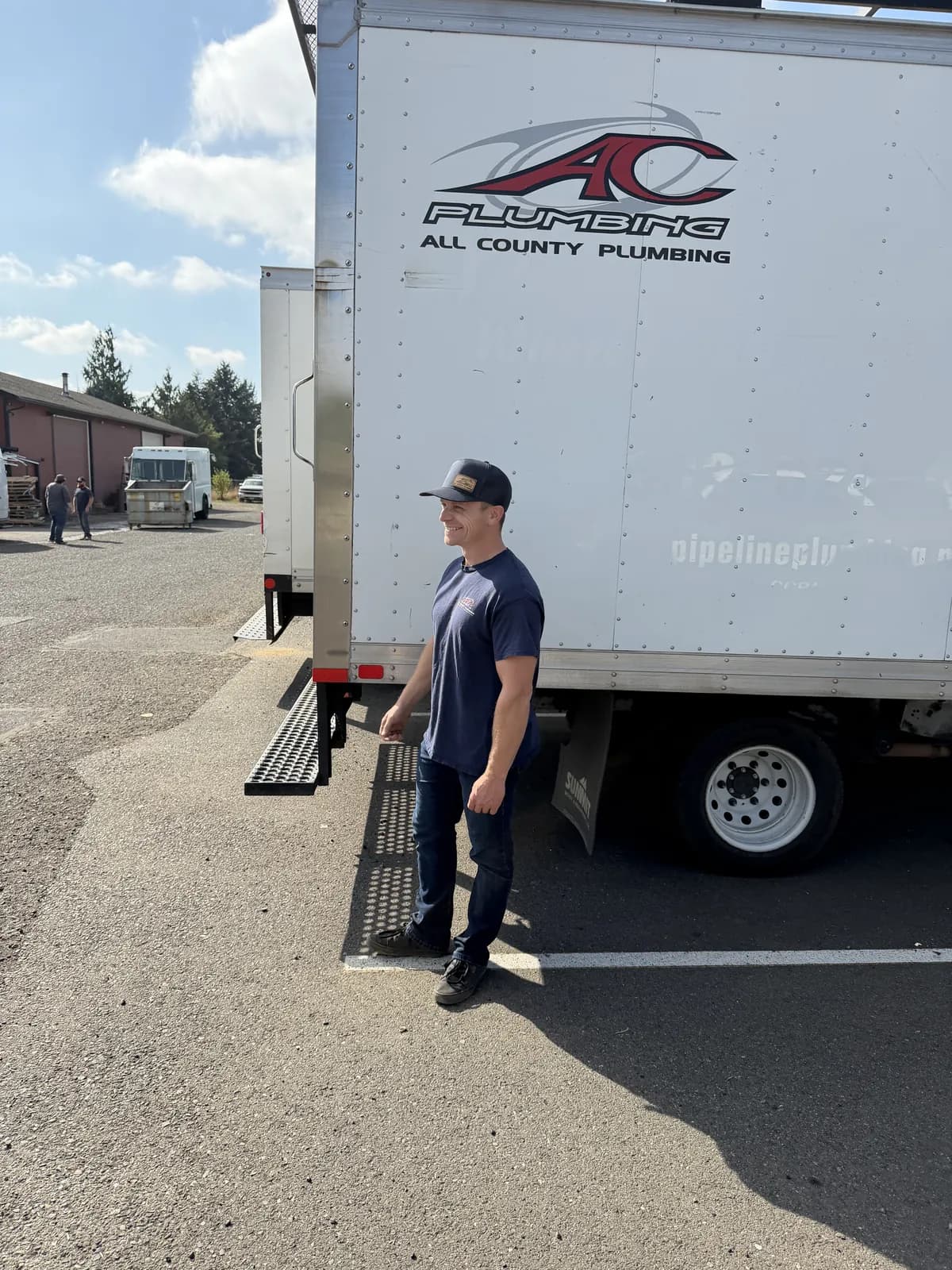 Josh beside a white All County box truck in the yard