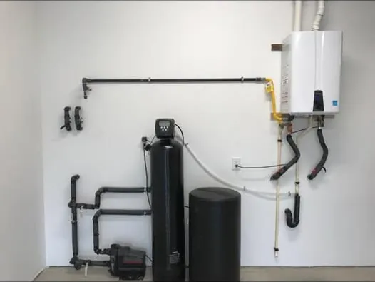 Wall-mounted tankless water heater with a filtration system below it